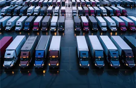 Commercial fleet includes rows of parked semi trucks and delivery vans